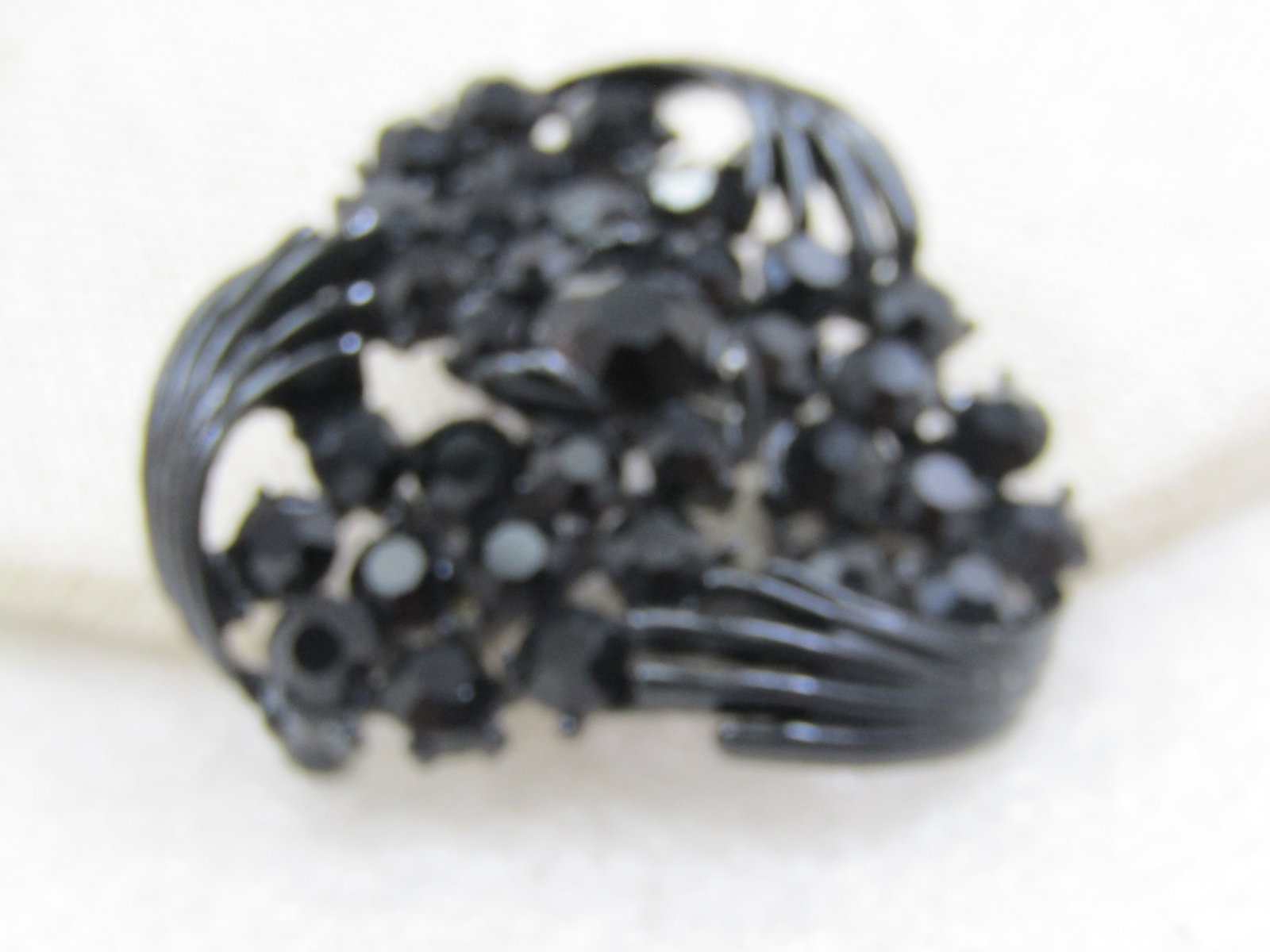 Vintage Black Rhinestone & Metal Brooch, 1.5", 1960's: Vintage Black Rhinestone & Metal Brooch, 1.5", 1960's. It has a triangular design with curved strands and blossom cluster of black rhinestones. The pin is painted black metal. Not signed by the
