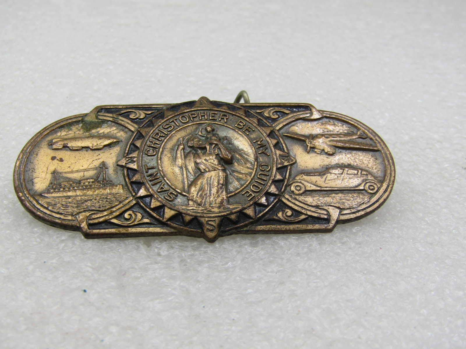 Vintage St. Christopher Be My Guide Car Brooch, Brass: Vintage St. Christopher Be My Guide Car Brooch, Brass. 2.5" wide and 1.25" tall with repousse images of a ship, plane, car, and blimp with St. Christoper in the center carrying a child and the wording