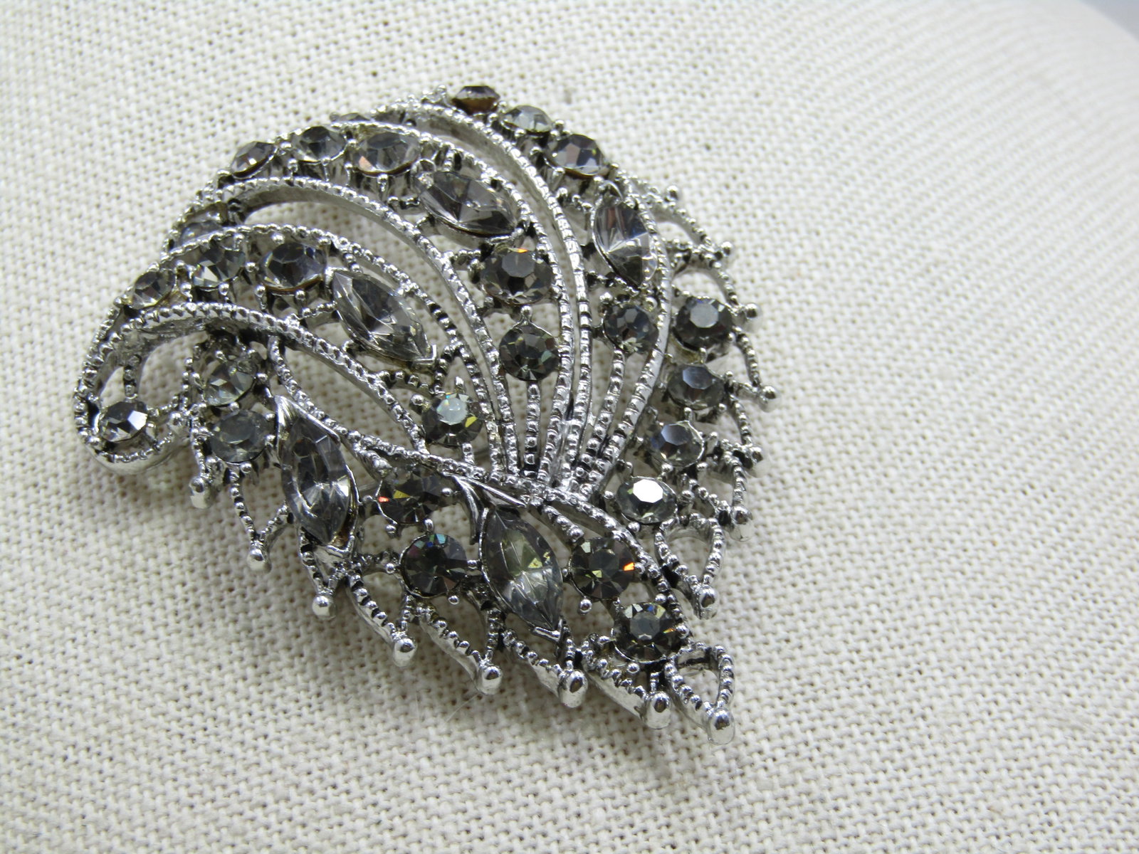 Vintage 1960's Smoky Rhinestone Brooch, 2.5": Vintage 1960's Smoky Rhinestone Brooch, 2.5" wide and 2" tall. A mix of round stones that are appx. 3mm to 4.5mm. The marquise stones are appx. 9.5mm by 4.5mm. Silver tone with a textured outline fram
