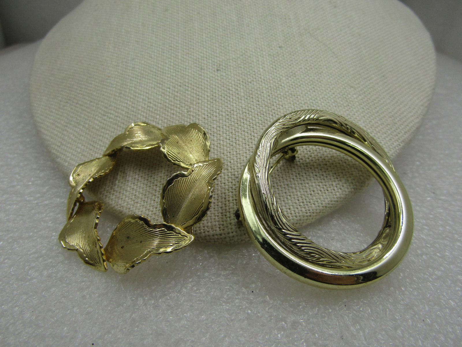 Vintage Pair of Circle Brooches, 1960's, Gold Tone: Vintage Pair of Circle Brooches, 1960's, Gold Tone. One is a stacked textured leaves circle brooch that is appx. 1.5" across. The second is a textured and smooth intertwined circle brooch, 1.75"