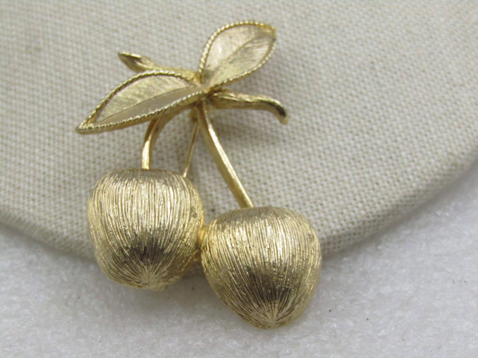 Vintage Cherry Stem Brooch, 1960's-1970's, Sarah Coventry: Vintage Cherry Stem Brooch, 1960's-1970's, Sarah Coventry. Gold tone with textured cherry and leaves and smooth stem. 2.75" long and 1.5" wide. Gold tone and in very good condition. (W2018.6 SS7257 J 