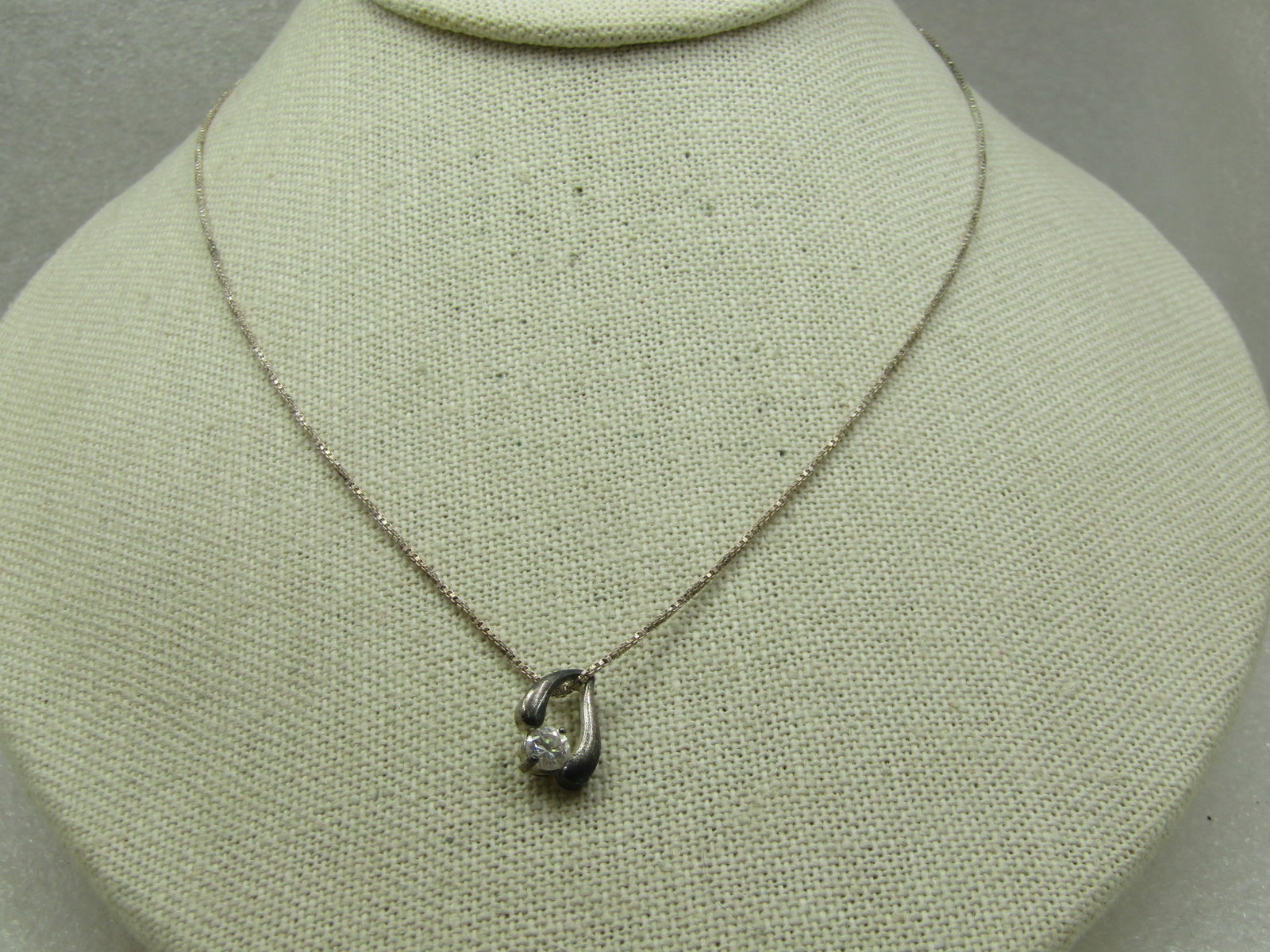 Vintage Sterling CZ Necklace, 18" Box Chain: Vintage Sterling CZ Necklace, 18" Box Chain. The CZ is appx. 4mm round clear CZ set between an offset drop curved frame that holds the CZ at the bottom of the pendant. Both pieces have been tested
