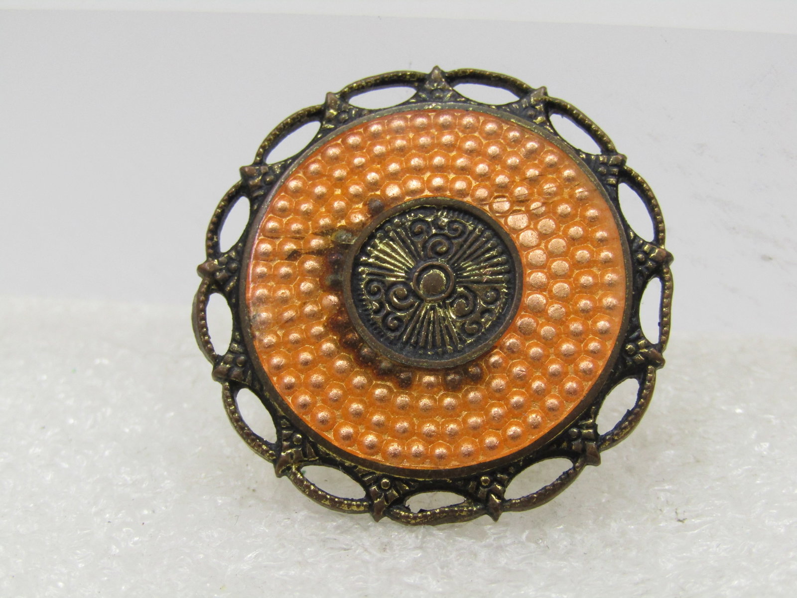 Vintage Orange Guilloche Circle Brooch, 1920's-1930's: Vintage Orange Guilloche Circle Brooch, 1920's-1930's. 1-1/8" wide with a textured frame with pointed accents that reach out to the outer frame. The center has a ray and scrolled design that is appx.