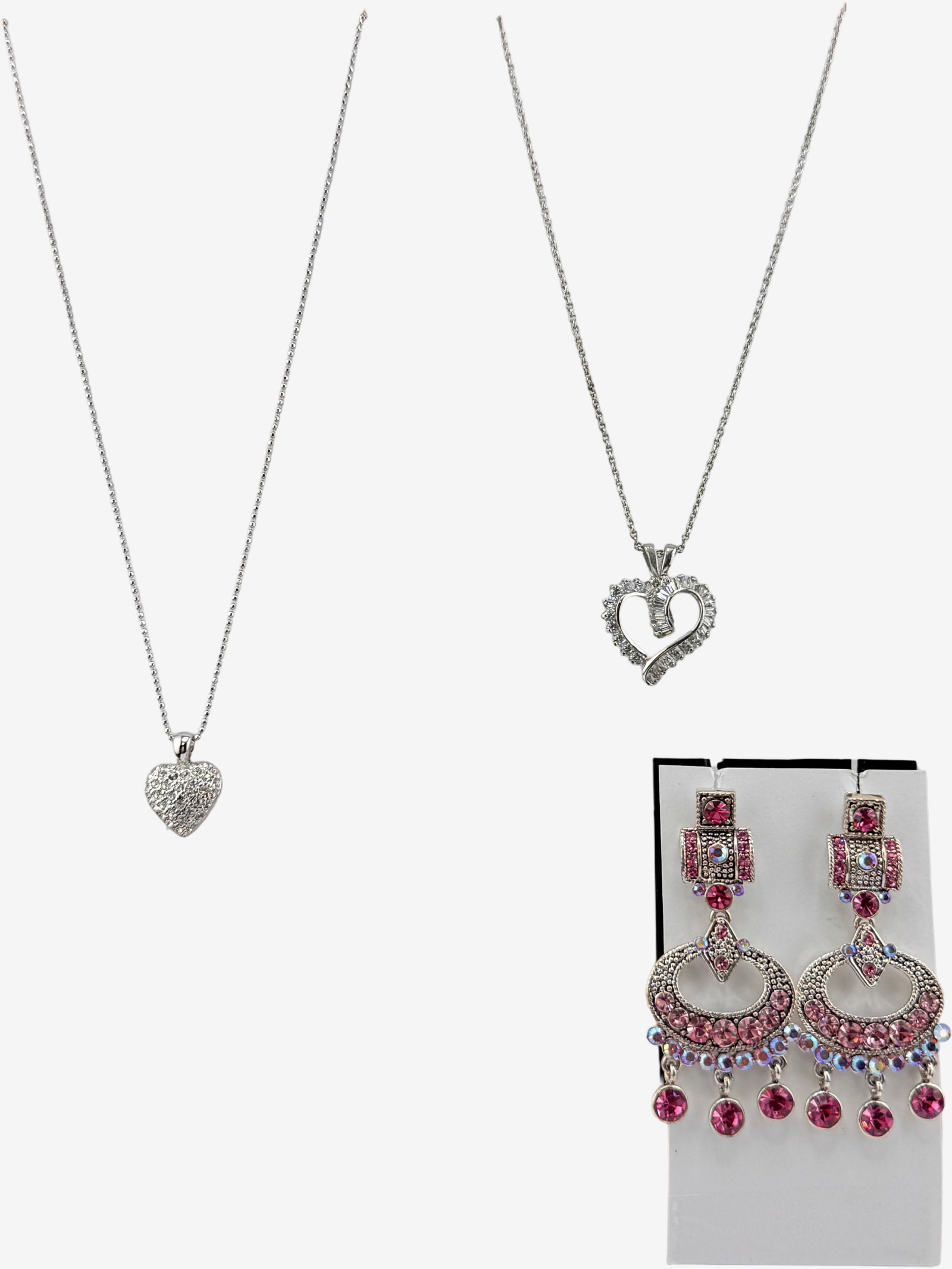 Three-Piece Silver-Tone Lot with Pink and Clear Gemstones: This lot features three pieces of silver-tone costume jewelry, including two necklaces with heart-shaped pendants and a pair of dangle earrings. Each necklace features a delicate silver-tone chain. On