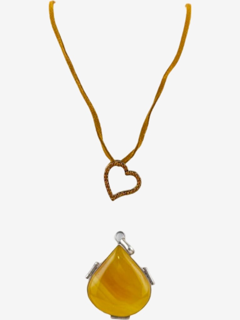Two Decorative Pendants: A Rhinestone Heart Pendant on Cord and a Sterling Silver Yellow Agate: This lot includes two distinct pendants: a heart-shaped pendant adorned with rhinestones, suspended from a golden cord, and a teardrop-shaped yellow agate pendant set in a sterling silver. The heart