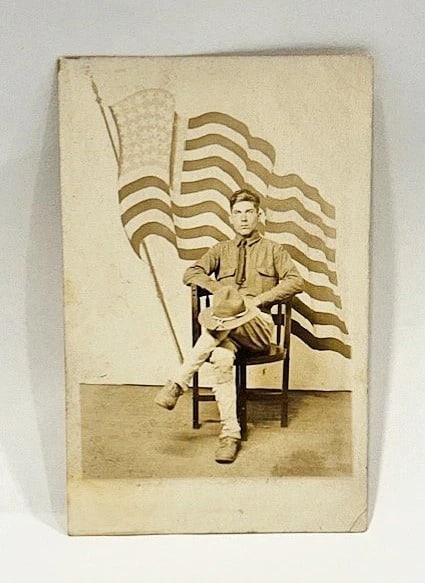 RPPC Real Photo Postcard Patriotic Soldier w American Flag 1900: Real photo postcard of an American soldier sitting on a chair before a background of a painted American Flag. Card is unused and in good condition - please see the images. Circa 1900 - 1909.