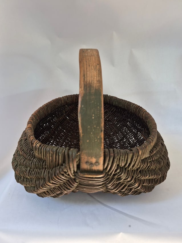 19th c painted buttocks basket: An unusual butt basket, made with reeds. Very good condition with only one snapped reed and one piece of a reed missing, as shown in photo. Deep olive green dry surface. Good wear on the handle. 12"
