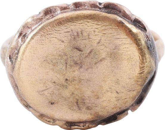 MEDIEVAL RING, 10TH CENTURY AD SIZE 6 ¾: Gilt bronze, size 6 ¾ for wear by a man or woman. 2.4mm well rounded section band flaring modestly to the shoulders. Raised oval bezel with recesses, concave scallops emulating flower petals and 