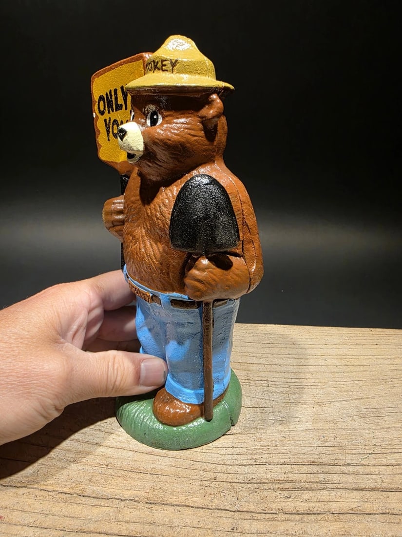 8" Cast Iron Smokey The Bear Coin Bank: 5 L x 3.5 W x 8 H Such a good reproduction cast iron bank depicting Smokey Bear, known for his role in wildfire prevention. This particular bank is designed in an antique vintage finish, hand-painted