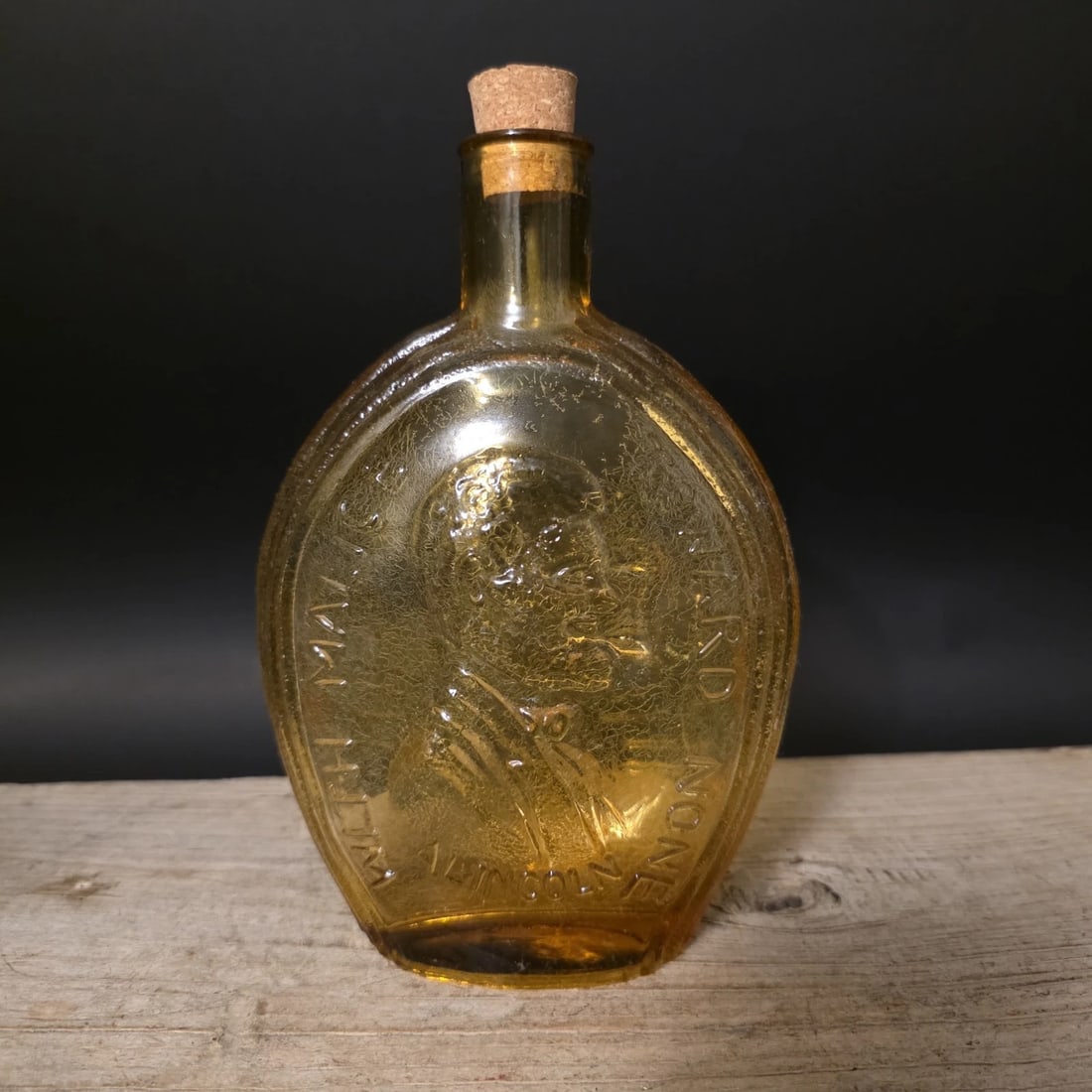 8" Amber Glass Abraham Lincoln Decanter Flask Bottle: Reproduction Amber glass bottle flask featuring an embossed portrait of Abraham Lincoln with patriotic lettering surrounding the image. Bottles of this type are inspired by commemorative historical