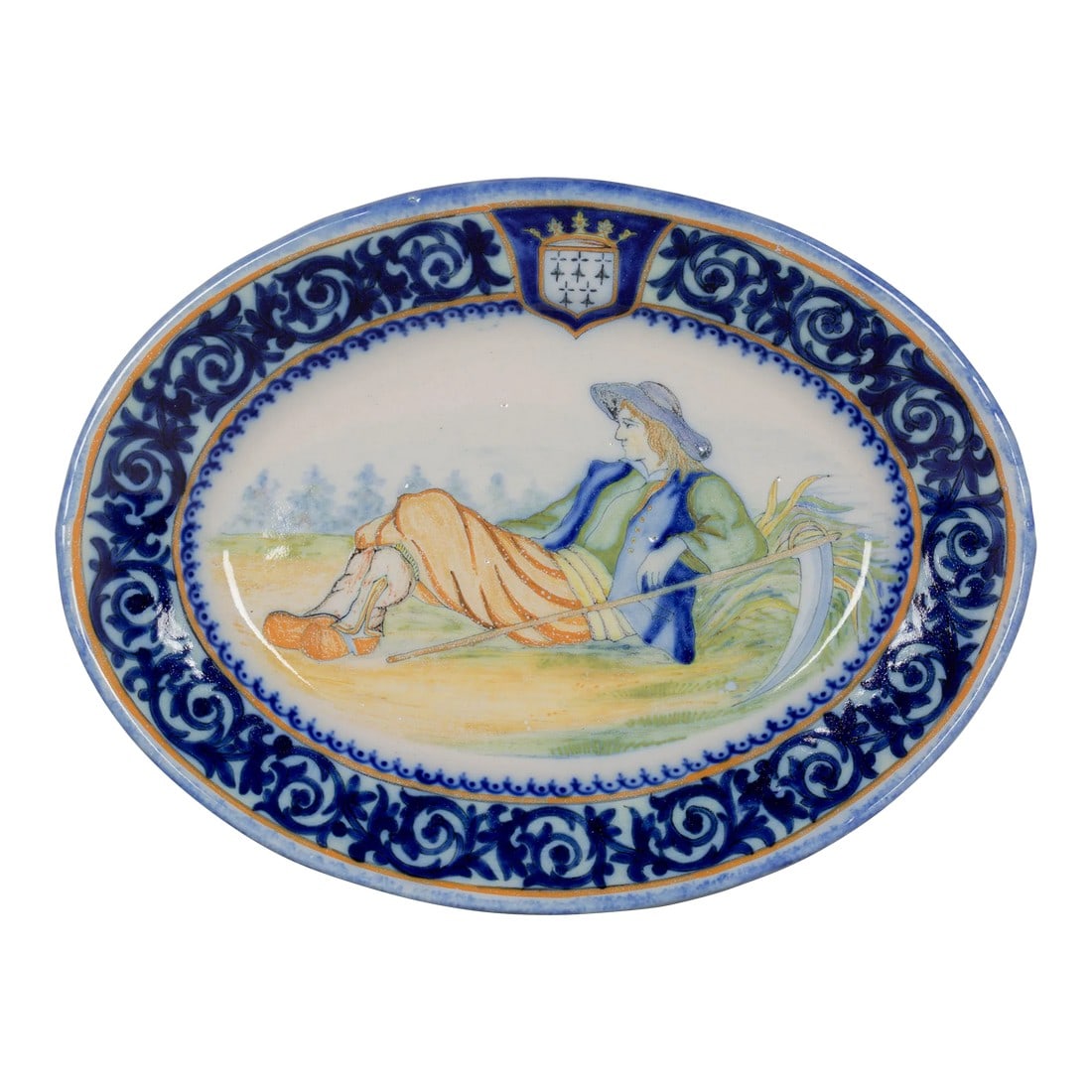 French Henriot Quimper Faience Platter: An early 20th century Henriot Quimper French faience decorative oval platter, hand painted scene of a farm worker at rest with his scythe. Wide blue foliate border with the crest of Brittany. Mark