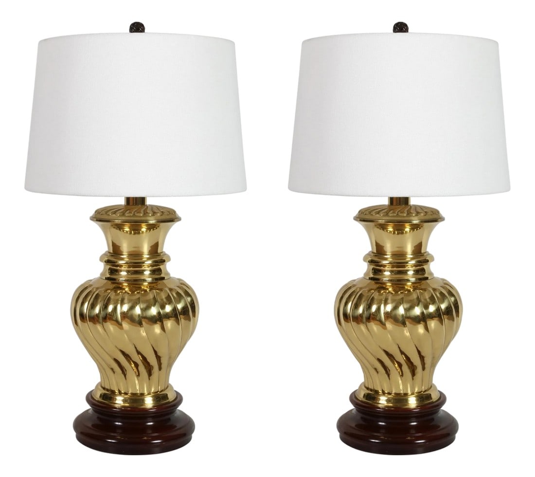 Pair of Hollywood Regency Style Brass Ginger Jar Lamps on Wood Bases: A vintage pair of Hollywood Regency style table lamps featuring a classic ginger jar inspired shape rendered in warm, high-shine brass and anchored by rich, dark wood plinth bases. The sculptural, rib