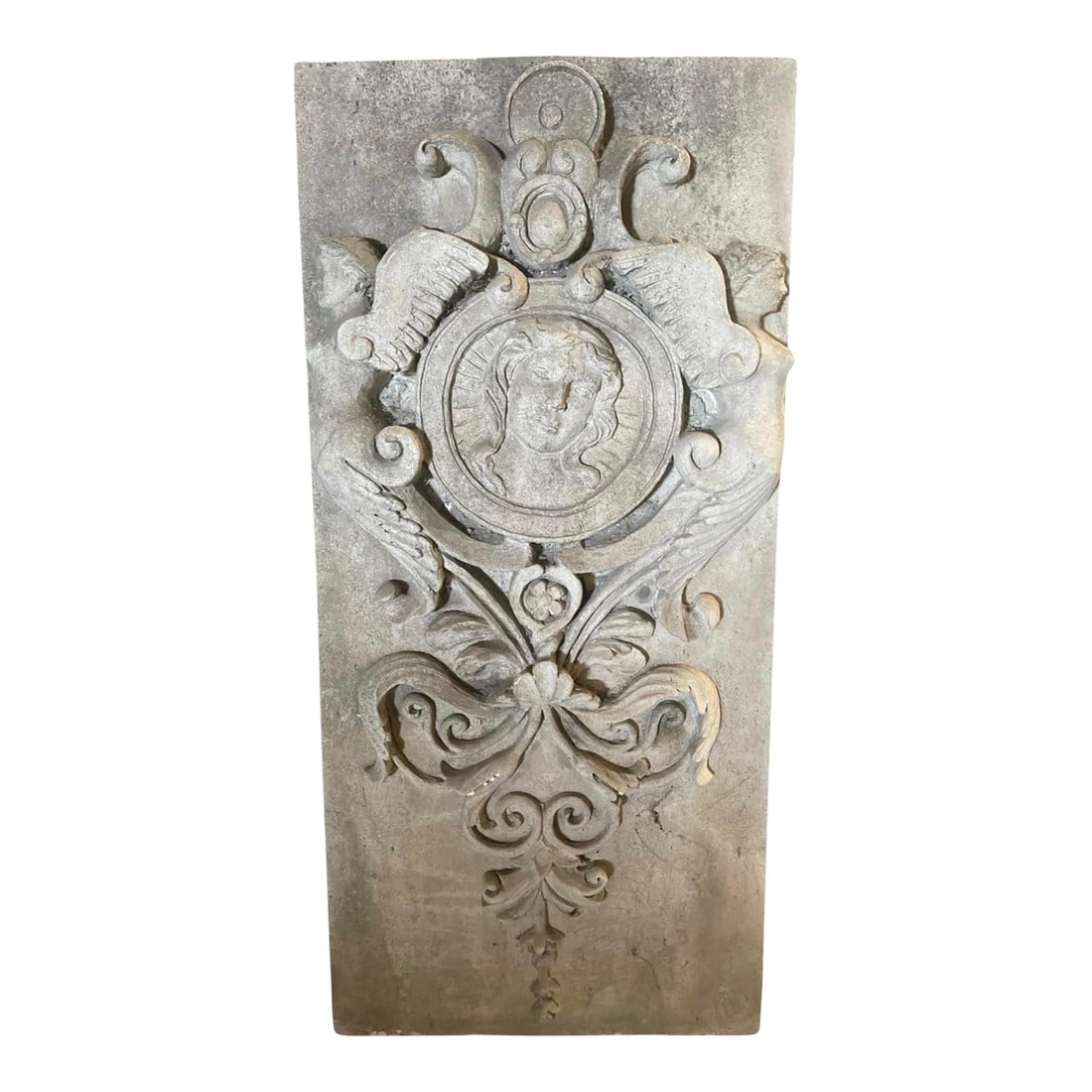 Neoclassical Style Relief-Carved Stone Wall Panel: This elegant cast stone wall panel features a rich array of classical motifs, centered by a circular medallic relief depicting a youth's face in profile, surrounded by a radiant sunburst. The central
