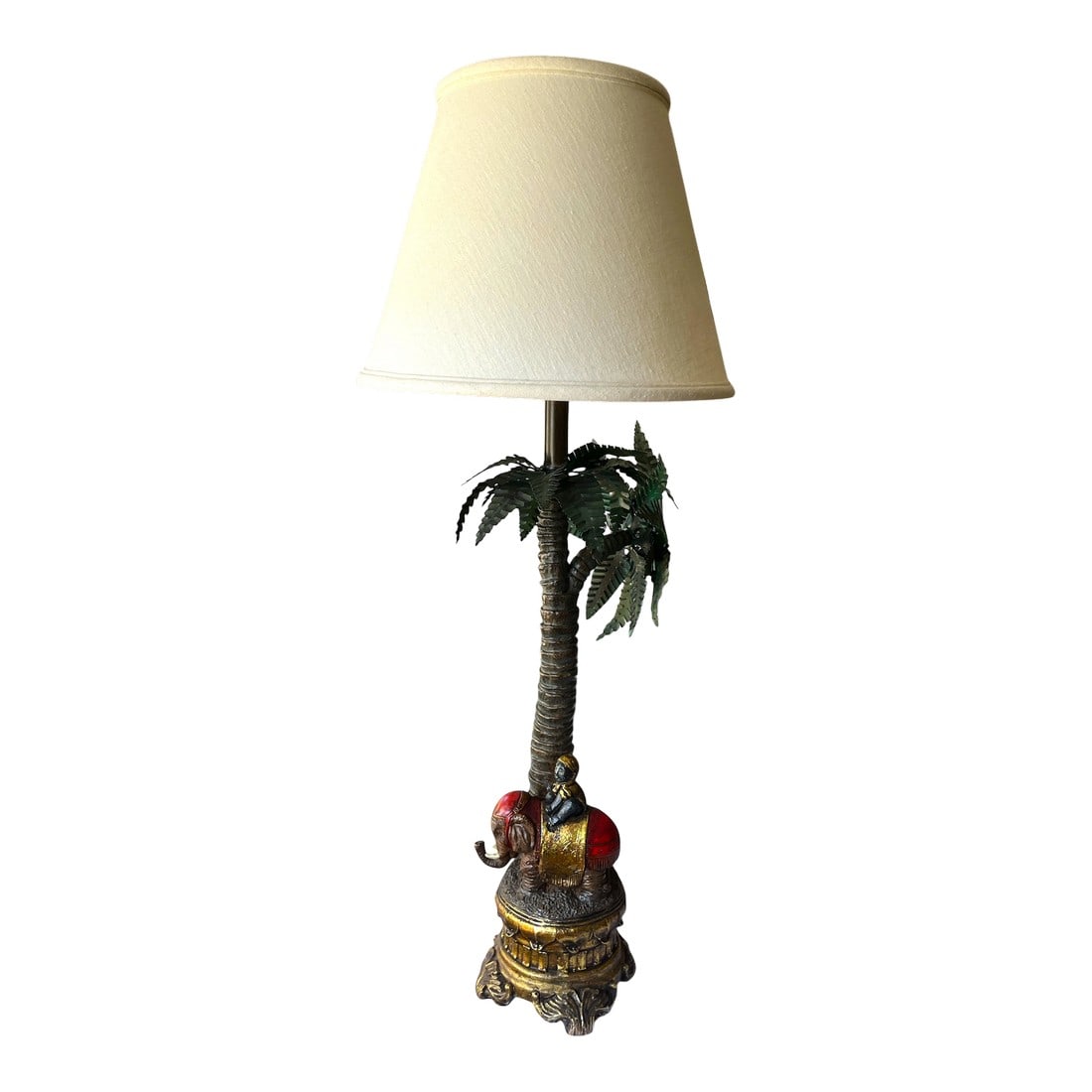 1990s Toile Elephant and Boy Tropical Palm Tree Table Lamp: 1990s tropical revival table lamp, featuring a richly detailed base with an elephant and rider under a towering palm tree. Hand-painted in warm tones of gold, red, and bronze with deep green metal toi