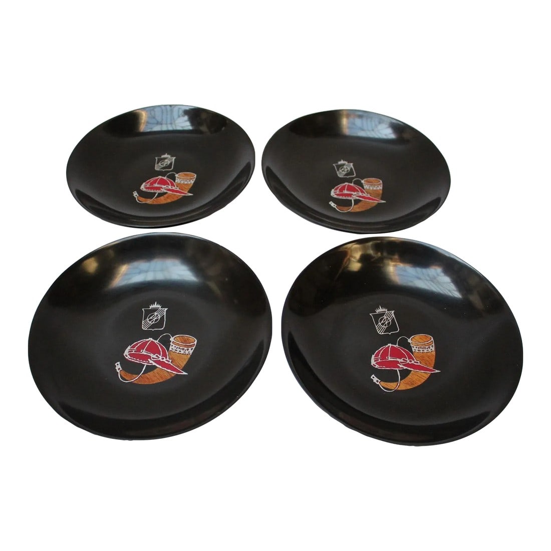 Set of Four Mid-Century Black Resin Inlaid Couroc Hunting Motif Plates: Set of four small, round decorative dishes/hors d'oeuvre plates/ashtrays depicting props for a hunt (cow horn and hunting cap) by Couroc of Monterey, California (circa 1960s). Composed of a black lacq