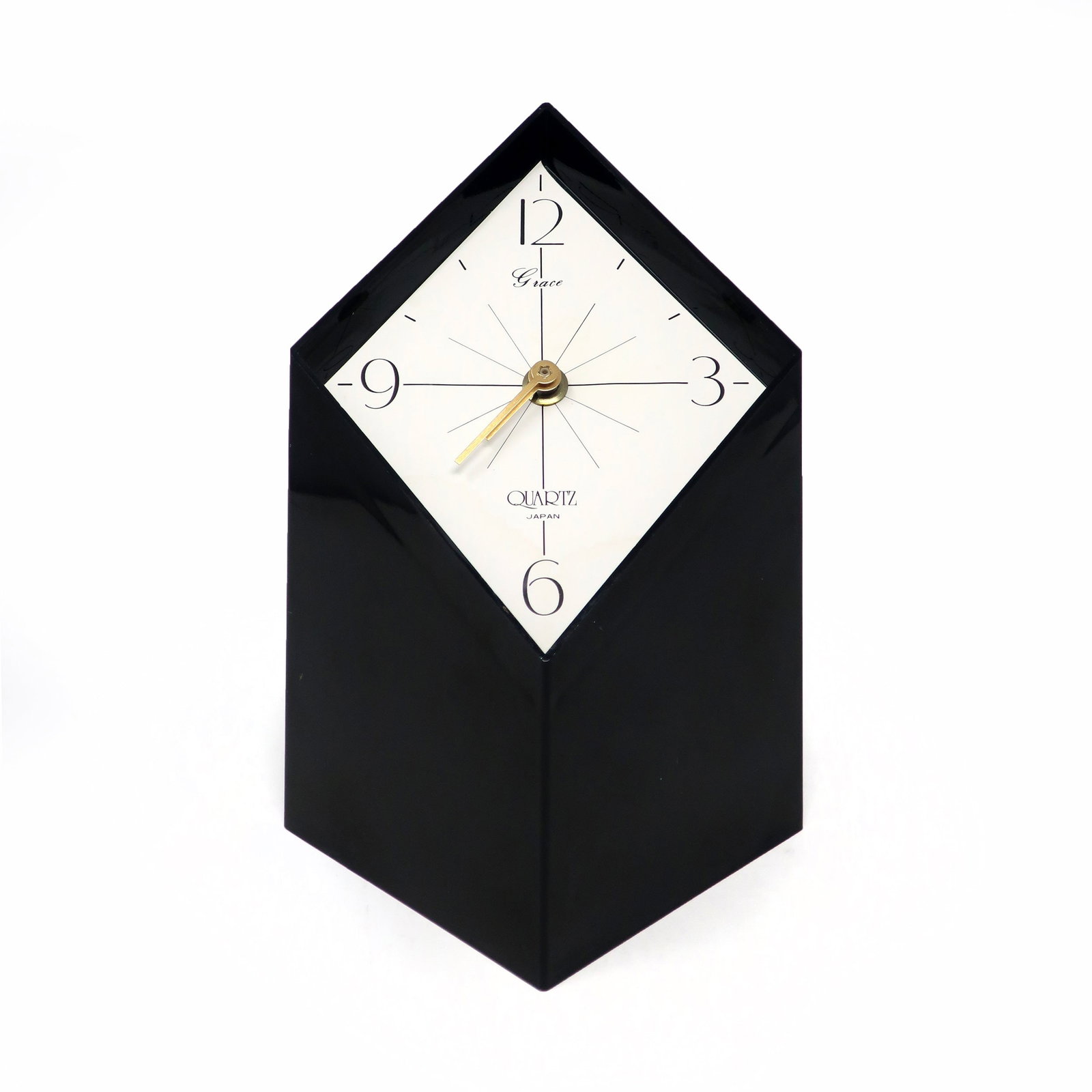 1970s Japanese Black Lucite Clock by Grace: An amazing vintage black desk or table clock with a black plastic body and a white face made by Grace, a Japanese company. Diamond shaped with a diagonal face, giving it a fantastic three dimensionali