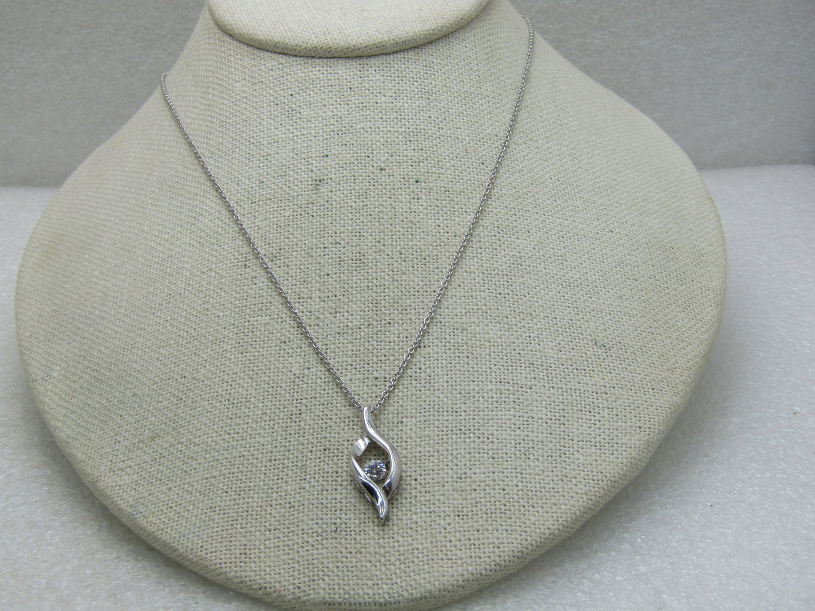 Pivoting CZ Flame Necklace, 18", Silver Tone: Pivoting CZ Flame Necklace, 18", Silver Tone. 4mm brilliant CZ inside a raised flame-like pendant - the CZ can pivot. Pendant is 1" tall. The pendant is slightly over 4mm thick with a bridged edge/ Lo