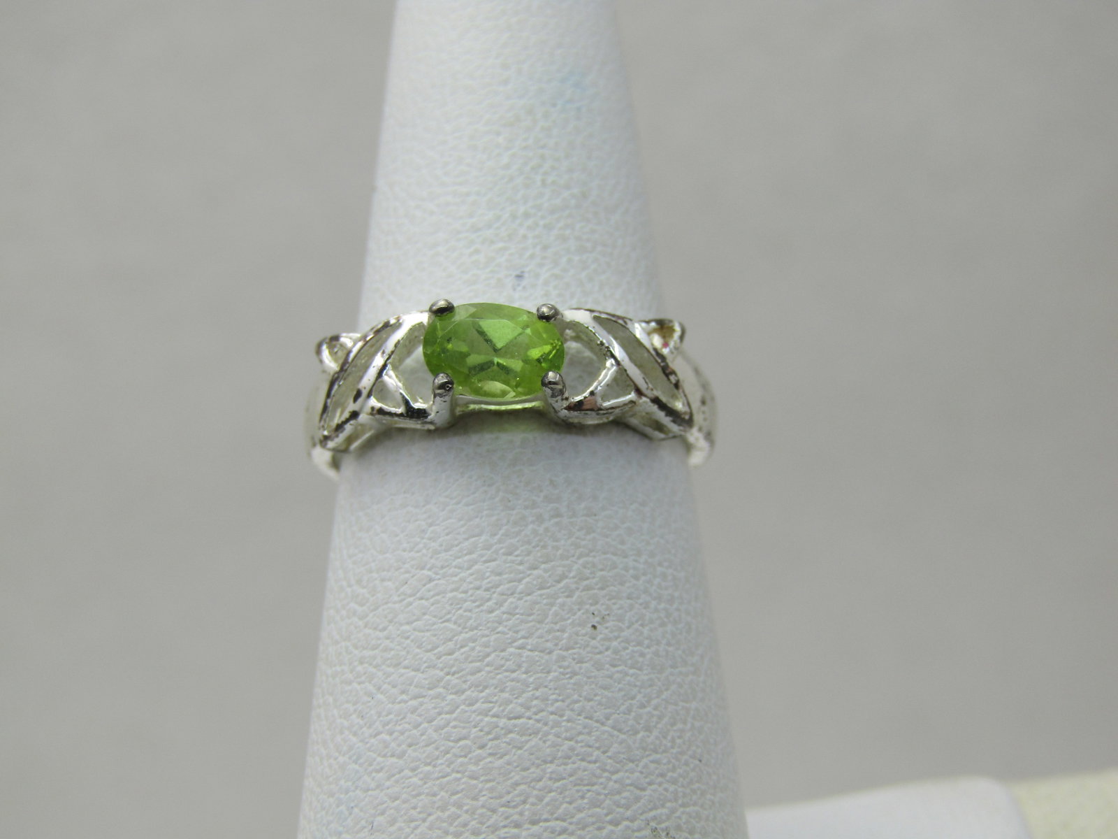 Sterling Plated Peridot X Ring, Sz. 6.75, 5mm: Sterling Plated Peridot X Ring, Sz. 6.75, 5mm X pattern on bad. The stone is oval and set on it's side. 6mm by apx. 4mm. 2.5.mm at the back of the finger. It is marked .925 and signed HAN Thai (Thaila