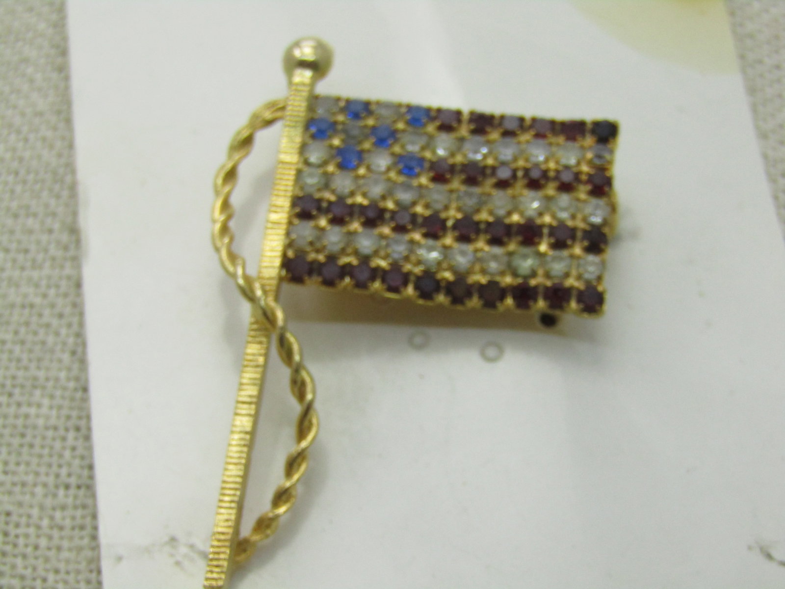Vintage Blue & Clear Rhinestone USA Flag, Gold Tone, 2" by 1.5": Vintage Blue & Clear Rhinestone USA Flag, Gold Tone, 2" by 1.5". Flag pole with rope, 1970's-1980's. Very good condition. Not signed by the maker. (INV. W.2720.15.7 SS2676 LET LD 10/11/20) Reserve: $2