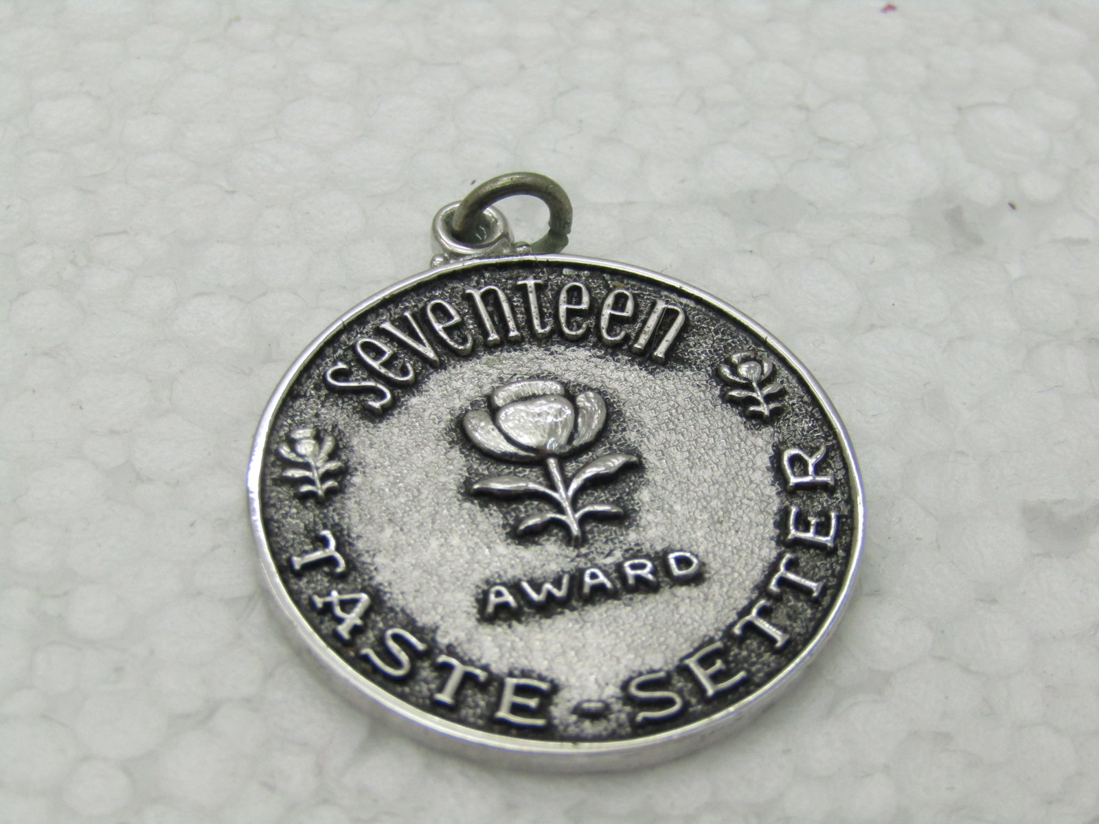 Vintage Sterling Silver Seventeen Taste Setter Award Medallion, 11.50 gr. 1-1/8": Vintage Sterling Silver Seventeen Taste Setter Award Medallion, 11.50 gr. 1-1/8" and is appx. 2mm thick. It has a rose in the center, repousse with a rose on the left and right of it at the edge. It