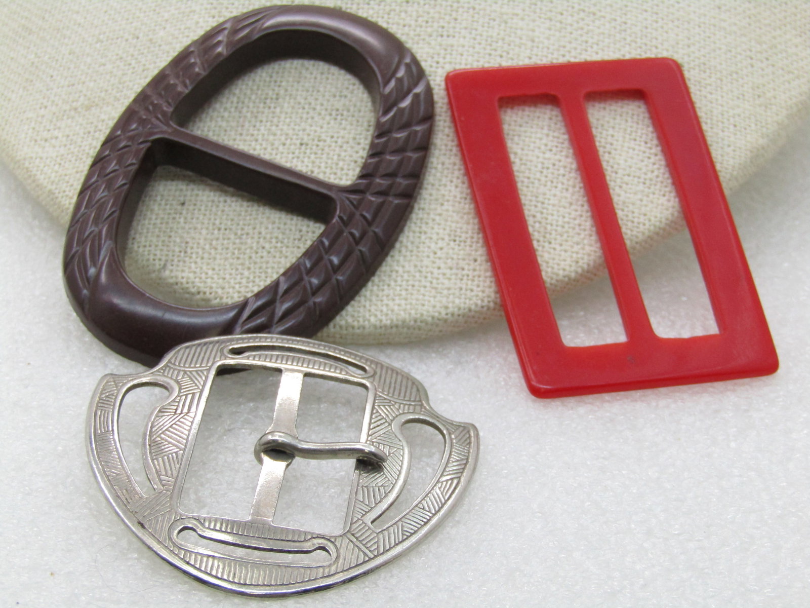 Vintage Buckle Lot, 2 Bakelite, 1 Metal, 1940's-Mid-Century: Vintage Buckle Lot, 2 Bakelite, 1 Metal, 1940's-Mid-Century The brown oval is appx. 3" by 2" with a grooved design on the long side. There is a red bakelight rectangular buckle that is 2.5" by 1.5".