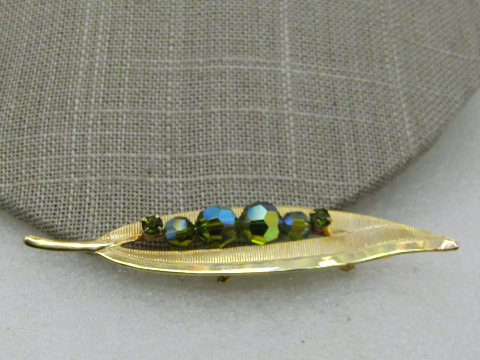 Vintage Aurora Borealis Beaded Leaf Brooch, 3.25": Vintage Aurora Borealis Beaded Leaf Brooch, 3.25" by 5/8", 1960's. Gold Tone. Graduated faceted aurora borealis cryst beads ranged from 5.5mm to 7.5mm and mounted in the open center of the leaf with a