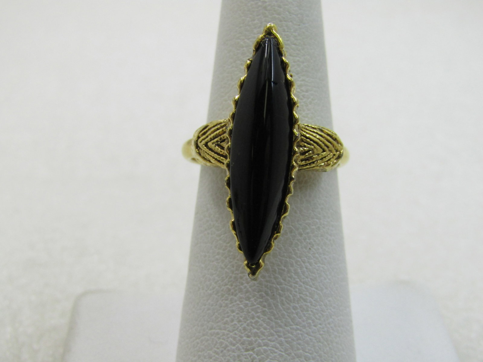 Vintage Vogue Signed Black Stone Pointed Ring, Adjustable: Vintage Vogue Signed Black Stone Pointed Ring, Adjustable. Gold tone. The black stone is appx. 24.5mm long and 5.5mm wide set in a gold tone bezel with textured accents on each side of the stone that