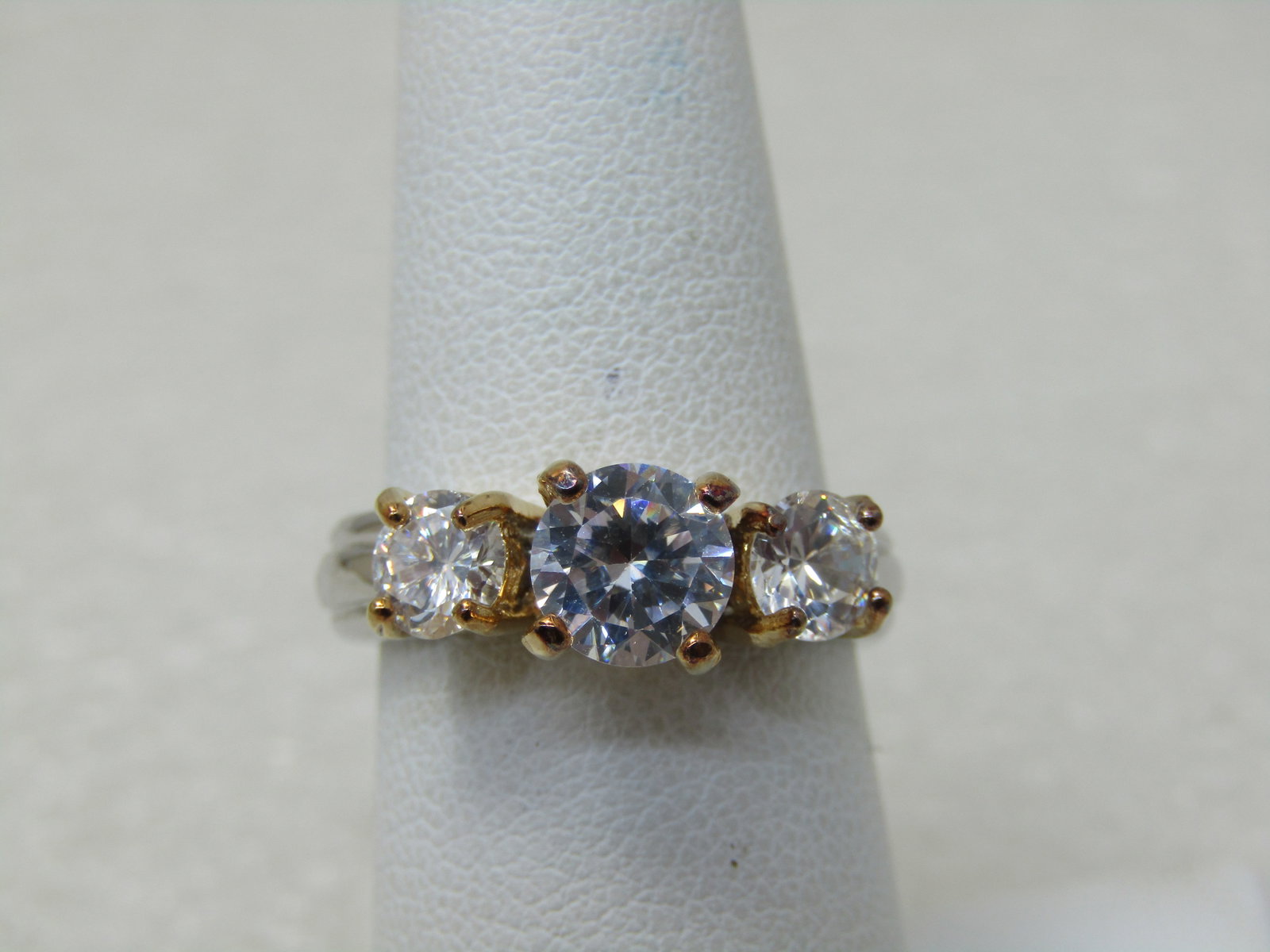 Lind Silver Plated Triple CZ Ring, Two-Tone, Sz. 7.25: Lind Silver Plated Triple CZ Ring, Two-Tone, Sz. 7.25 The center stone is larger and equivalent to 1CT with two 1/2 carat CZ, one on each side. Silver Plated Band with gold tone prongs. Striking ring 