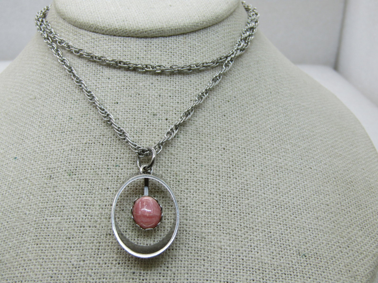 Vintage Rhodocrosite Necklace, 24", Silver Tone, 1970's, Southwestern Appeal: Vintage Rhodocrosite Necklace, 24", Silver Tone, 1970's. It has an oval rhodocrosite pink stone that is appx. 10.5mm by 8mm set in a scalloped bezel inside an angled oval open framed pendant that is a