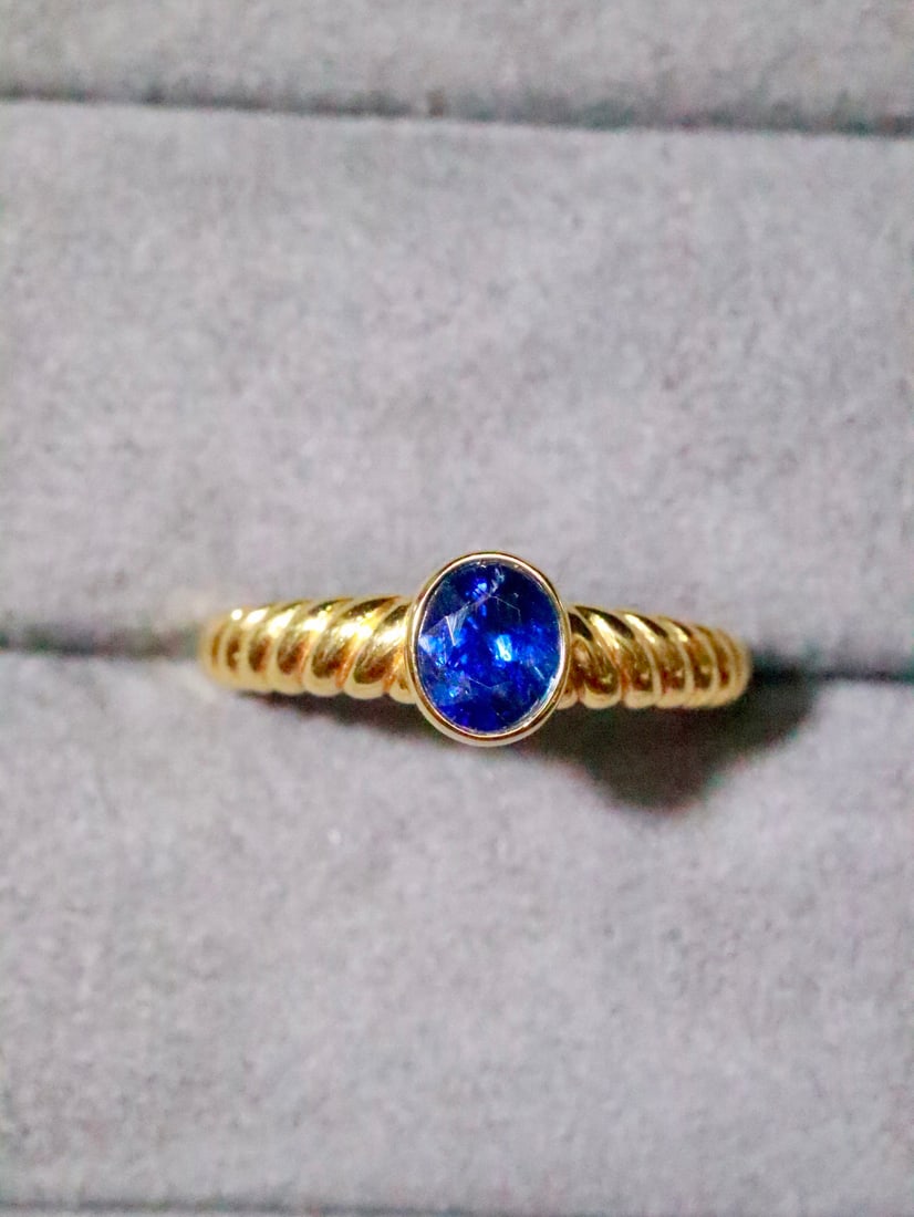 18K Blue Sapphire Ring: Title: 18K Blue Sapphire Ring Description: This 18K gold blue sapphire ring stands out with its simple and stylish design. The sapphire's vivid color and sparkling brilliance exude an aura of