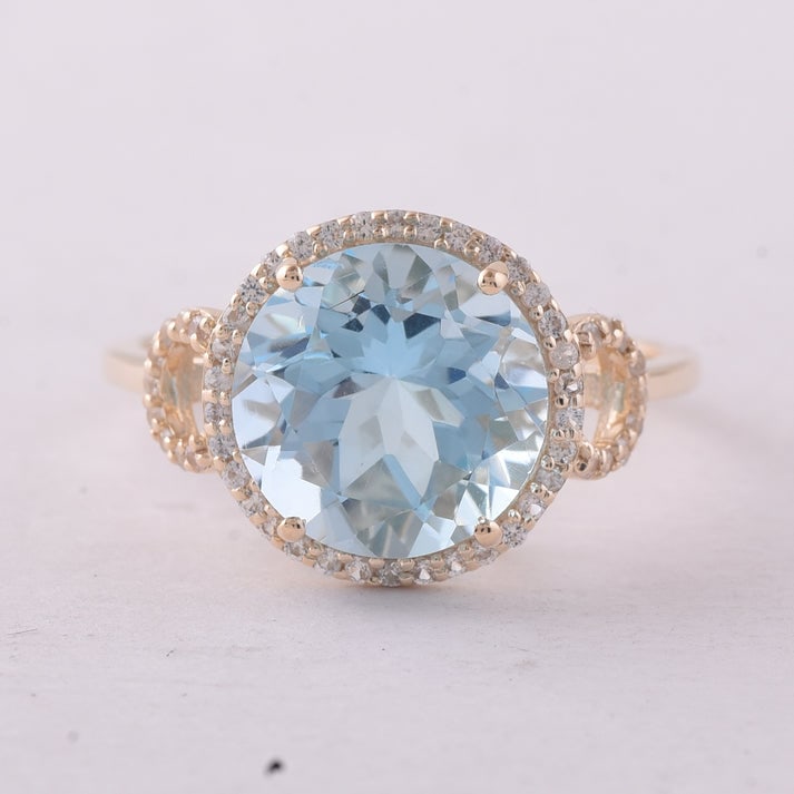 4.80 Ct Round Blue Topaz 9K Gold Ring: 4.80 Total Carat Blue Topaz 9K Gold Ring Specifications: Total Weight 2.769 g Center Gemstone Blue Topaz Gemstone Carat Weight 4.58 Carats Gemstone Measurements 10 mm Additional Gemstones White Sapphi