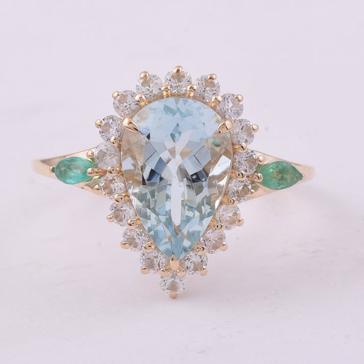 3.53 Ct Pear Aquamarine 9K Gold Ring: 3.53 Total Carat Aquamarine 9K Gold Ring Specifications: Total Weight 2.697 g Center Gemstone Aquamarine Gemstone Carat Weight 2.55 Carats Gemstone Measurements 12X8X5.30 mm Additional Gemstones Emera