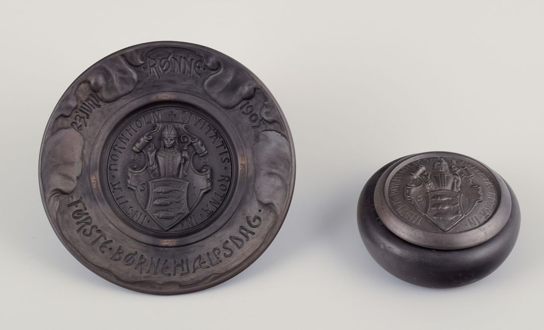 Hjorth, Bornholm. Wall plaque and lidded jar in black terracotta. Early 20th C.: Hjorth, Bornholm. Wall plaque and lidded jar in black terracotta. Wall relief title: "Forste Bornehjaelpsdag Ronne 1905" Early 1900s. Marked. In excellent condition. Wall relief: D 17.0 cm. Lidded jar