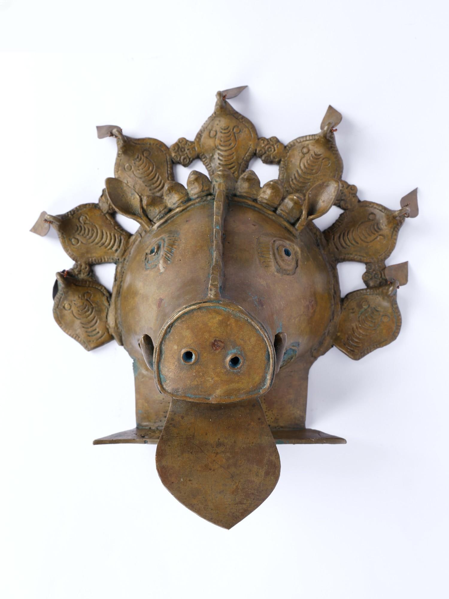 10" Tribal Varaha Head Bronze Statue from Tikamgarh: Description: This statue from Tikamgarh is a remarkable representation of Lord Vishnu’s Varaha avatar, uniquely interpreted through the lens of tribal artistry from the Tikamgarh region. This sculpt