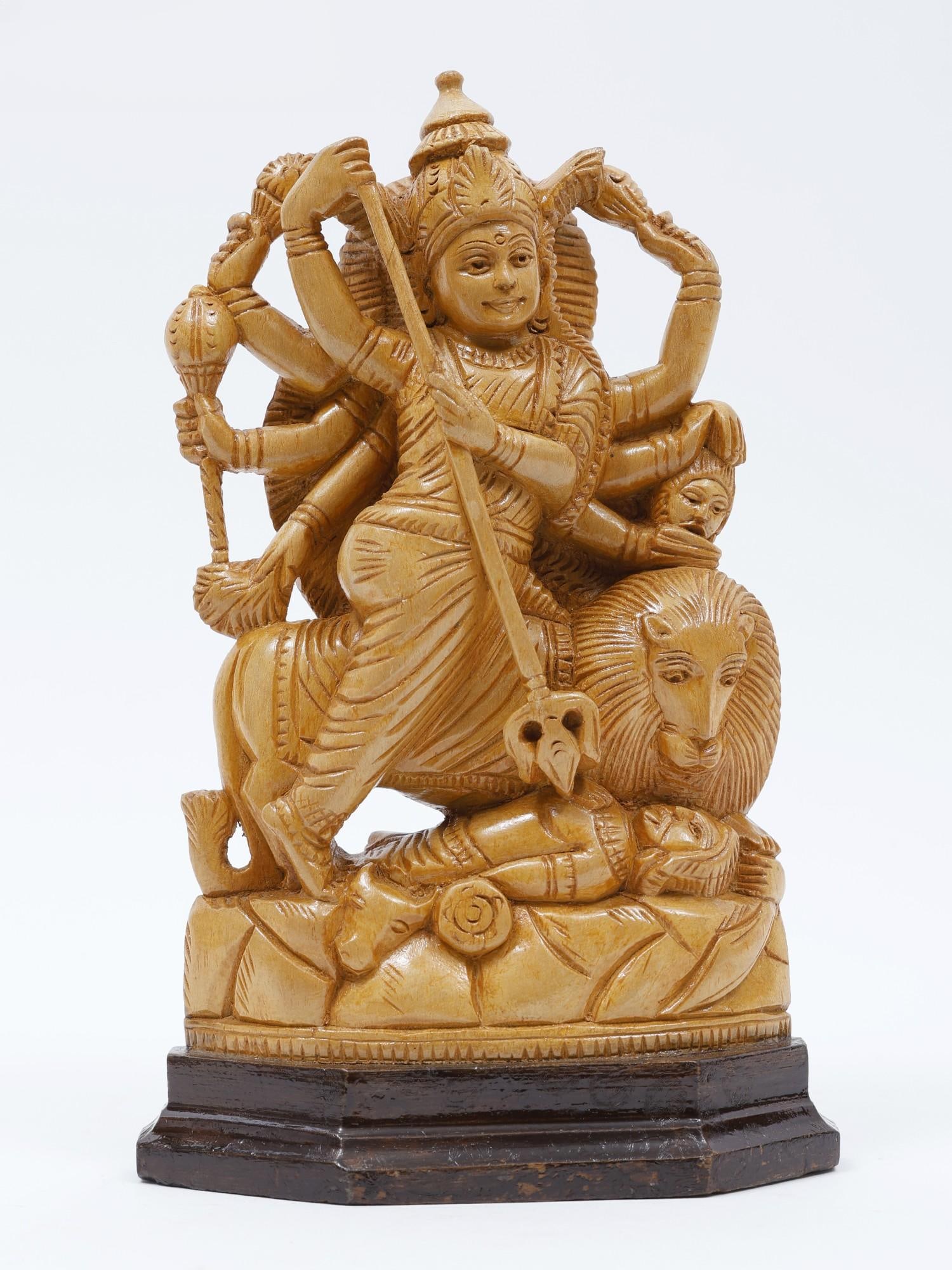 9" Goddess Durga (Mahishasuramardini) Wood Carved Statue: Description: Her Trishula piercing the body of the buffalo demon and her lion staring at the vanquished enemy, this wooden image of Mahishasuramardini Maa Durga combines her maternal and warrior aspec