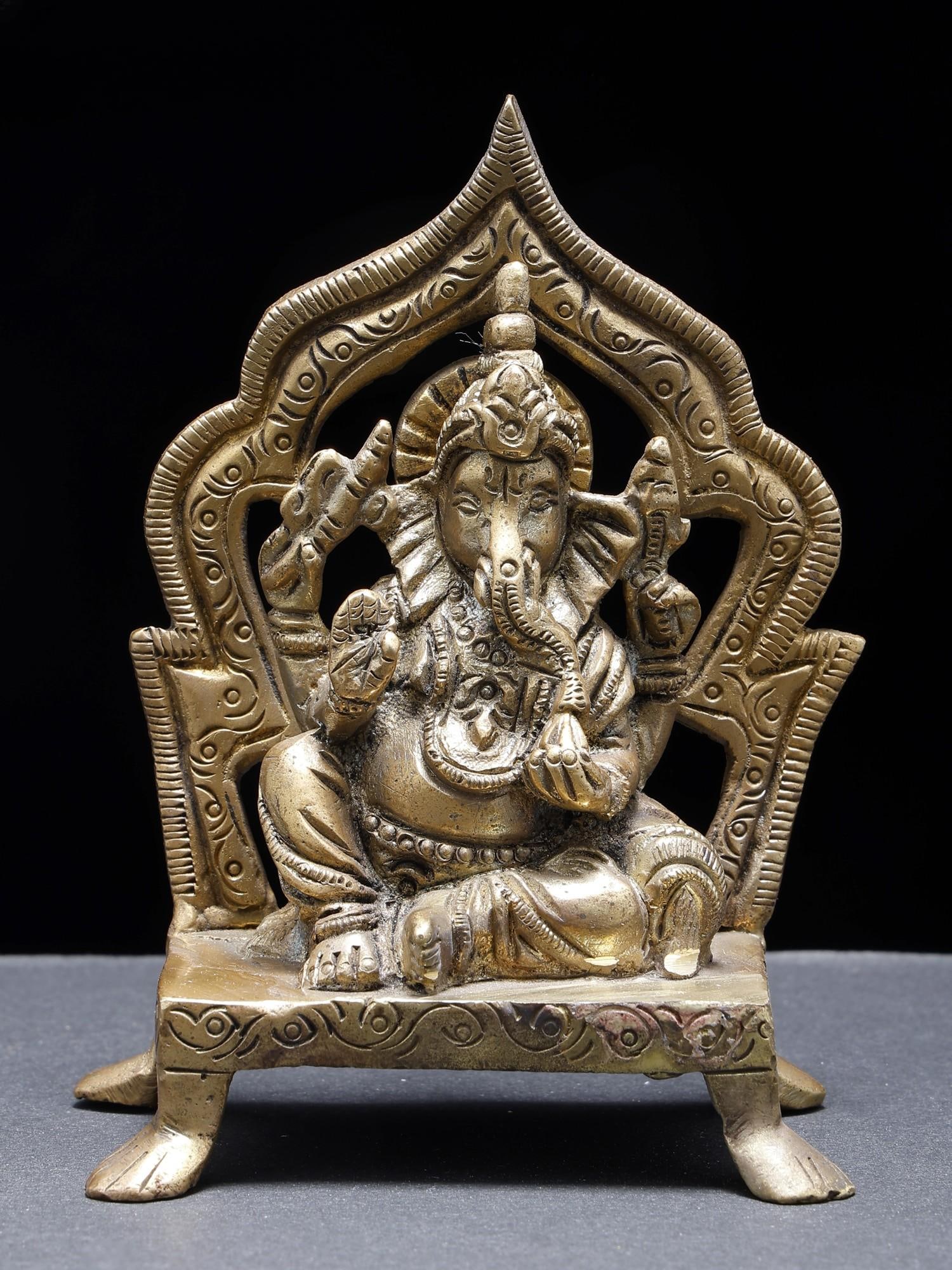Blessing Lord Ganesha Seated on Throne /Small Brass Statue: Description: The auspicious Lord Ganesha is presented in this small brass statue in his "Raja Ganapati" form, embodying the regalia and fortune that he bestows upon the devotees. A traditional