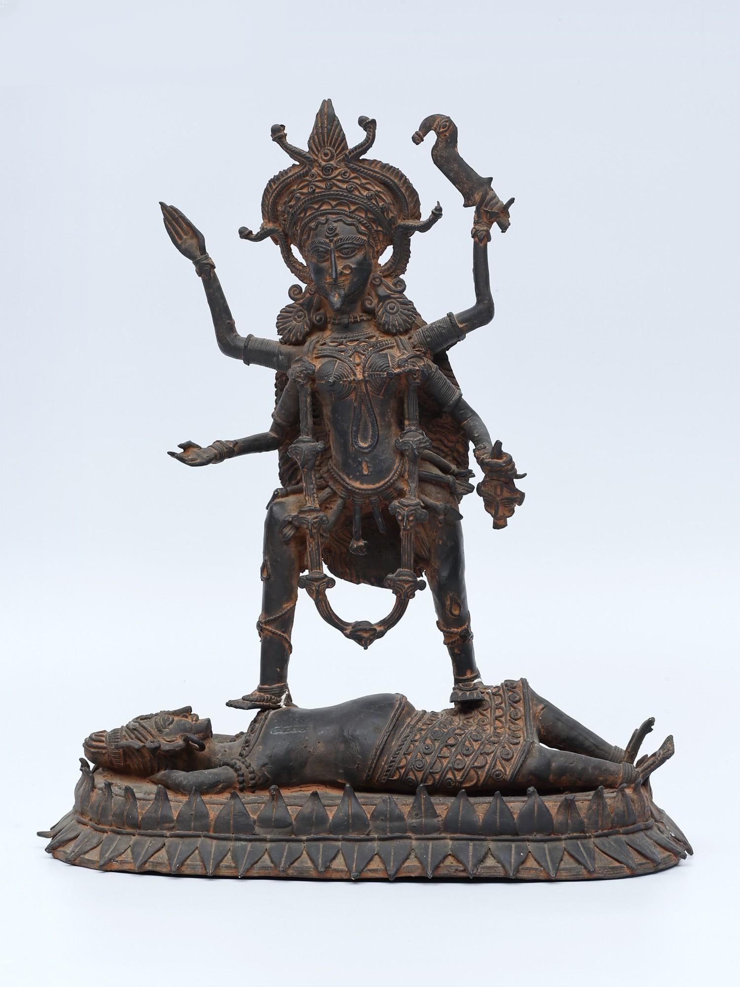 11" Goddess Kali Standing on Lord Shiva /Tribal Bronze Statue: Description: This statue depicts Goddess Kali, a fierce manifestation of divine feminine energy, standing confidently in the supine form of Lord Shiva. Symbolizing the dynamic interplay of creation an