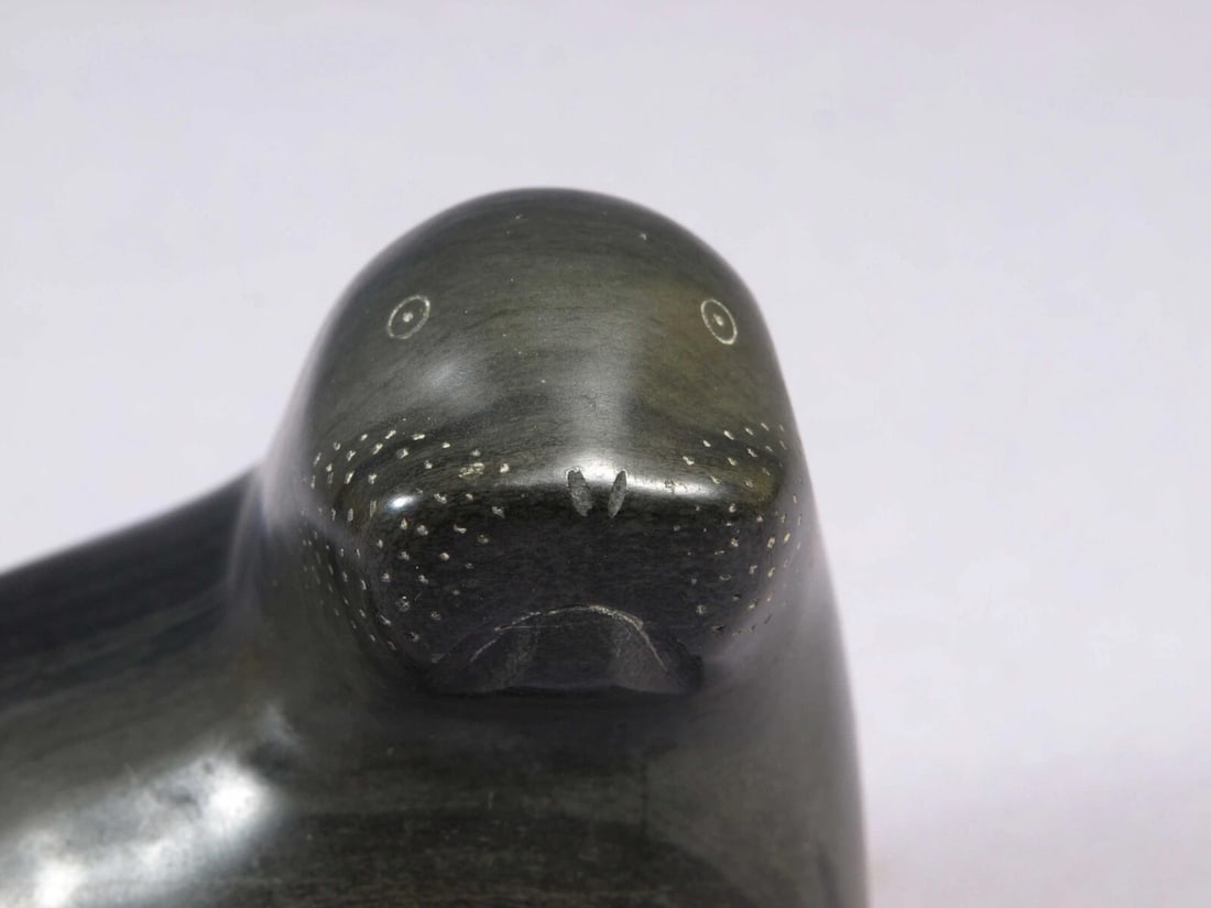 Inuit Canada Carving Sea Lion Seal Soapstone SIGNED 1959 Adamie Inukpuk sticker: This is a vintage Native American Eskimo Inuit Figurine. It is attributed to the artist Adamie Inukpukwith. It is is made in 1959. It retains an original Canada Eskimo Art Sticker. The figurine is