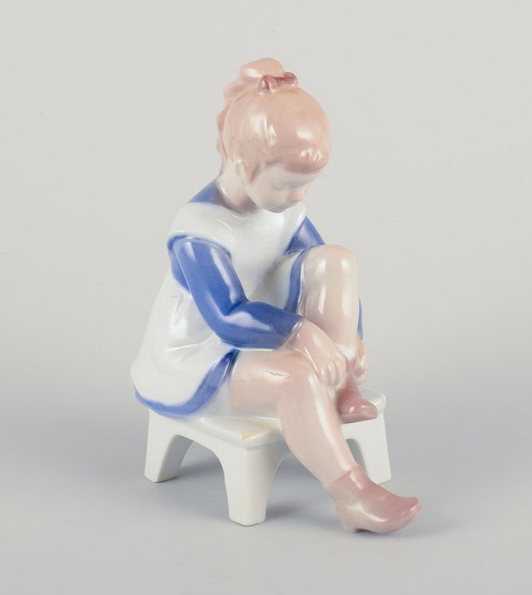 Bing & Grøndahl, Denmark. Porcelain figurine. Sitting girl tying a shoelace. Mid-20th century. (1 of 10)
