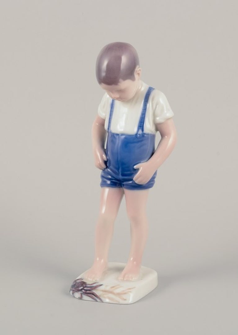 Bing & Grøndahl, Denmark. Porcelain figurine of a boy and crab. Mid-20th century.: Bing & Grøndahl, Denmark. Porcelain figurine of a boy and crab. Model number 1870. Mid-20th century. Marked. In perfect condition. First factory quality. Dimensions: H 20.0 cm x W 7.2 cm.; Bing &