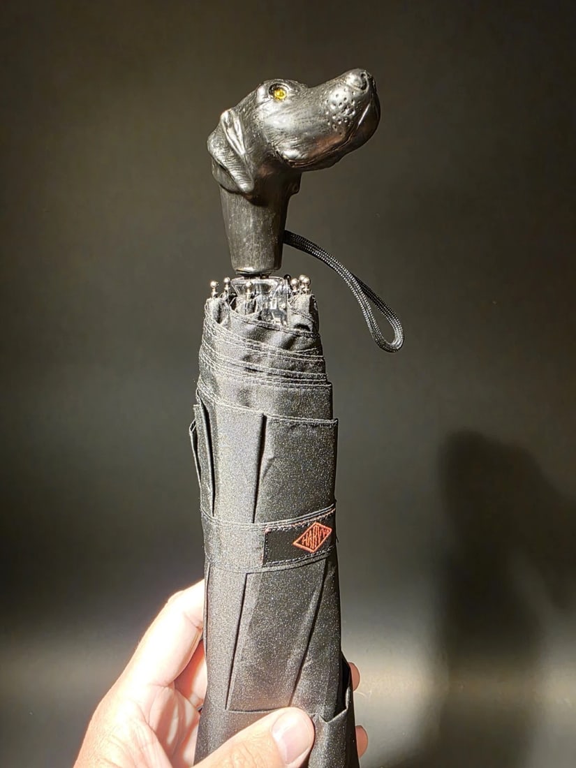 11 1/2" Black Lab Dog Head Umbrella: Mini black nylon folding umbrella, 8 ribs, 23" canopy, manual open. Comes with sheath and black wrist strap. Measures 11 1/2" when closed, weighs 10oz. The item in the images is a model. Each item