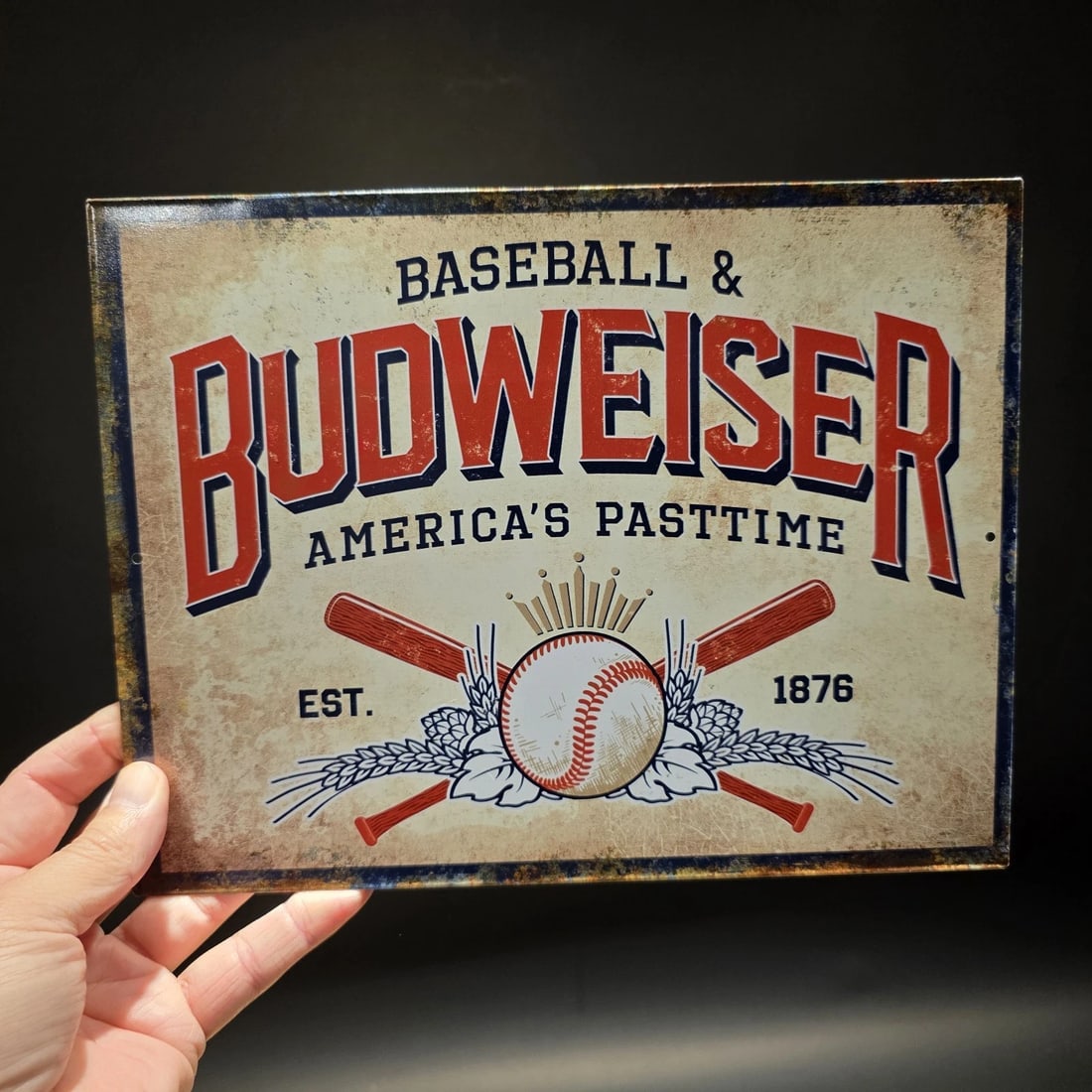 Budweiser Baseball Tin Sign Beer Advertising: 10.75 x 8.25 Budweiser advertising sign featuring a baseball and crossed bats design with the phrase “America’s Pastime.” Beer and baseball have long been linked in American culture,