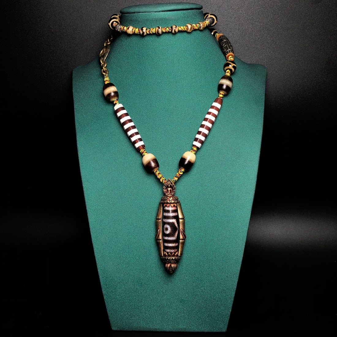 Old Tibetan Bronze Inlay DZI Agate Pendant & Necklace: Title: Old Tibetan Bronze Inlay DZI Agate Pendant & Necklace Origin: Chinese Date/Period: After1900 Materials: Bronze,DZI Agate Dimensions: 71x23x11(mm) 2.80x0.91x0.43(inches) Reserve: $150.00