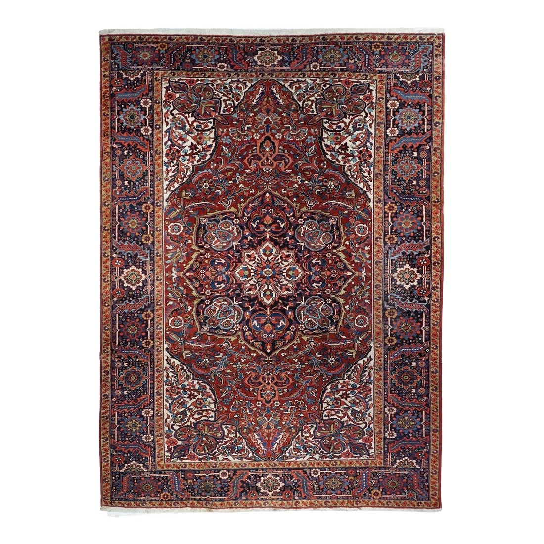 Vintage Heriz Rug 8'2'' X 11'7'': A semi-curvilinear Heriz style, developed first in the later 1940's, this prime example shows a shaped red field with a convex, octofoil navy medallion with pointed lobes, Ivory corners with angled