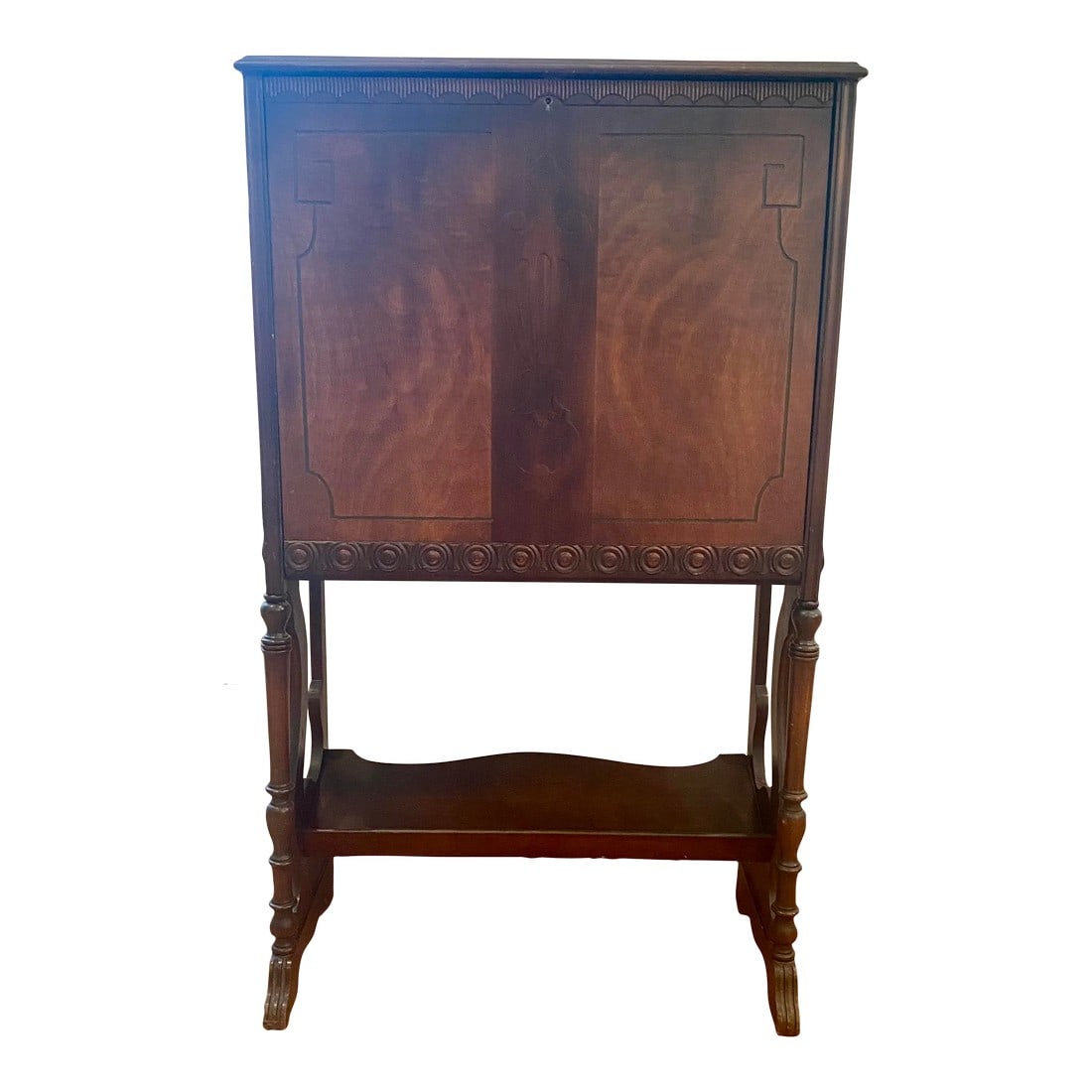 Vintage Mahogany Secretary With Flip Down Desk and Storage: Vintage wood tall secretary having pretty flat front with carved wood decoration and urn shape in the center. Lovely grain and particularly narrow depth. Turned legs have a lower tier for more storage