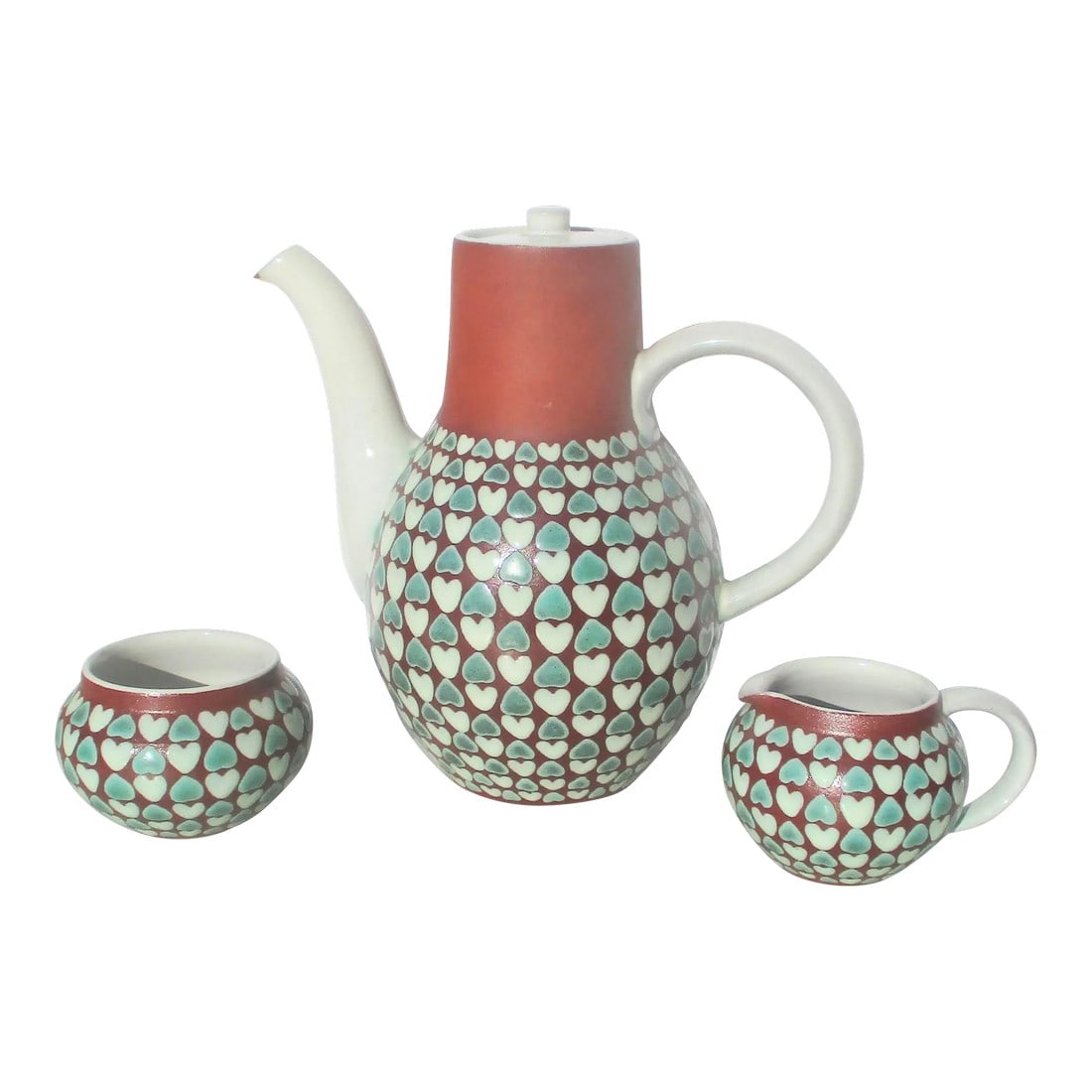 Tea, Sugar, and Creamer Set by Ioska Denmark -A Set of 3: Tea service by Ioska. Designed with a red ware body and patterned hearts in white and green. Milky white glaze over the inner walls and outer details. the red bisque is revealed as trim and bottom