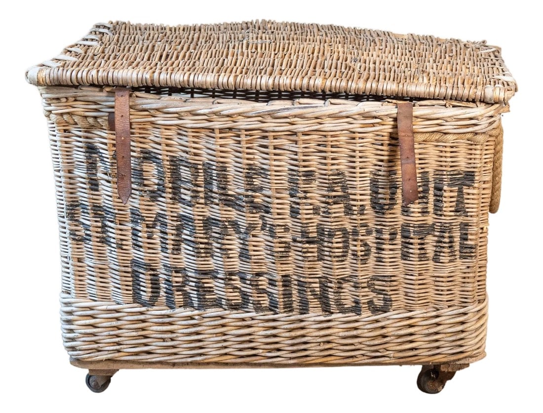 Early 20th Century English Wicker Laundry Basket on Wheels with Stenciled Labeli: A large and characterful English wicker laundry basket dating to the early 20th century, featuring original cast iron wheels and handwoven willow construction. The front is boldly stenciled with