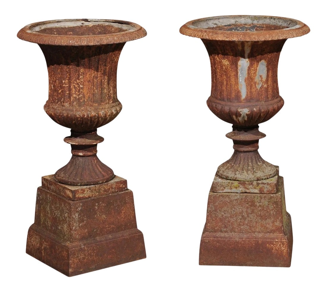 French 19th Century Iron Médicis Vases on Stepped Pedestals with Patina - A Pair: A pair of 19th century French rusty iron planters in the style of the vase Médicis, with pedestals and weathered patina. Created in France during the 19th century, each of this pair of iron
