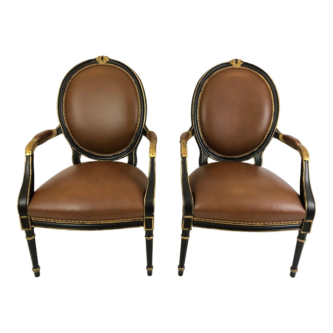 Century Supple Brown Leather and Ebonized Gilded Armchairs - A Pair: Impressive glamorous pair of roomy brown leather arm chairs having regal ebonized and gilded frames. The backs are oval shaped and beautiful front and back. Measures: Arm height 28 Seat depth 21.