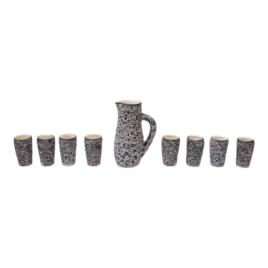 French Moderne Annecy Fat Lava Glaze Ceramic Drink Serving Set: Heavily textured ceramic nine-piece drink serving set including eight cups/tumblers and a single pitcher (ca. 1960s, Annecy, France). Fat volcano lava glaze in charcoal and white with subtle hues of